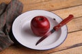 Closeup shot of a delicious and bright red apple and a knife on a white plate Royalty Free Stock Photo