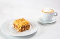 Closeup shot of a dessert plate near a cup of cappuccino isolated on white background Royalty Free Stock Photo