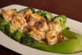 Closeup shot of a dish of prawns with broccoli and ham on a wooden surface