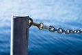 Closeup shot of a dock metal pole with metal chain with blue baclground
