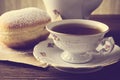 Closeup shot of donut with cup of tea on table in old-fashioned