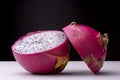 Closeup shot of a dragon fruit cut in a half on a white surface with a black background Royalty Free Stock Photo