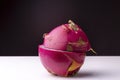 Closeup shot of a dragon fruit cut in a half on a white surface with a black background Royalty Free Stock Photo