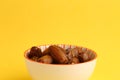 Closeup shot of dry dates fruit in a bowl on a yellow background Royalty Free Stock Photo
