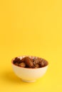 Closeup shot of dry dates fruit in a bowl on a yellow background Royalty Free Stock Photo