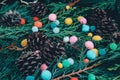 Closeup shot of evergreen tree branches and pinecones with small colorful pompoms