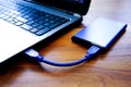 Closeup shot of an external HDD connected to a laptop on a wooden table Royalty Free Stock Photo