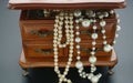 Closeup shot of extra long faux pearl necklaces in a wooden vintage trinket