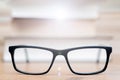 Closeup shot of eyeglasses on wooden table with books background Royalty Free Stock Photo