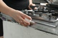 Closeup shot of a female hand cracking an egg on the side of a stove