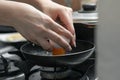 Closeup shot of female hands cracking open an egg into a metal pan