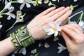 Closeup shot of female hands with green bracelet and a saffron flower
