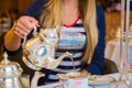 Closeup shot of a female pouring out tea from a decorative silver teapot Royalty Free Stock Photo