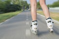 Closeup shot of female roller skates while rollerblading on blurred background of road