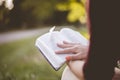 Closeup shot of a female sitting and reading the bible with a blurred background