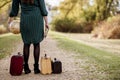 Closeup shot of a female standing on a pathway near her old suitcases while holding the bible Royalty Free Stock Photo