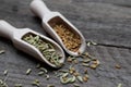 Closeup shot of fennel and fenugreek seeds in wooden spice spoons on a dark wooden surface