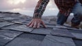 A closeup shot focuses on the skilled hands of a roofer as he carefully s and places shingles on a steep roof perfectly