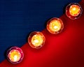 Closeup shot of four flower-shaped burning candles in a diagonal row on a red and blue surface