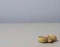 Closeup shot of four pistachios on the right lower corner on a grey background