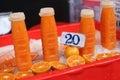 Closeup shot of four plastic bottles with orange juice and cut oranges in front, in a Thai market