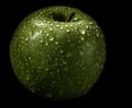 Closeup shot of a fresh green apple covered with water drops isolated on a black background Royalty Free Stock Photo