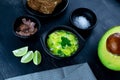 Closeup shot of fresh salad with avocado and lime, salami, bread on a black table Royalty Free Stock Photo