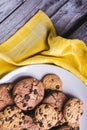 Closeup shot of freshly baked chocolate chip cookies in a white plate on a yellow textile Royalty Free Stock Photo