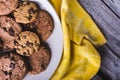 Closeup shot of freshly baked chocolate chip cookies in a white plate on a yellow textile Royalty Free Stock Photo