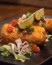 Closeup shot of fried mozzarella sticks with lime and salad in a black plate on the table Royalty Free Stock Photo