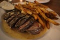 Closeup shot of fries and steak with a savory sauce plated on a white plate