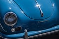 Closeup shot of the front of a vintage glossy sky blue Porsche parked under the shining sun
