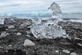Closeup shot of a glacial ice chunk on a dark rocky shore on a gloomy day in winter Royalty Free Stock Photo