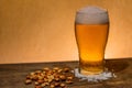 Closeup shot of a glass of beer and nuts on the table Royalty Free Stock Photo