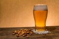 Closeup shot of a glass of beer and nuts on the table Royalty Free Stock Photo