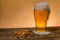 Closeup shot of a glass of beer and nuts on the table Royalty Free Stock Photo