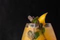 Closeup shot of a glass of mango and orange cocktail with mint