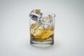 Closeup shot of a glass with whiskey and icecube on a white surface - great for a blog