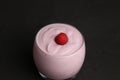 Closeup shot of a glass of yogurt with raspberry on black background