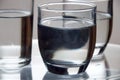 Closeup shot of glasses of cold water on a transparent surface