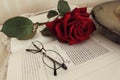 Closeup shot of glasses and rose on an open book Royalty Free Stock Photo