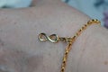 Closeup shot of a golden bracelet with an infinity charm