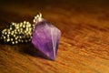 Closeup shot of a golden necklace with Amethyst stone on a wooden table Royalty Free Stock Photo