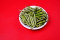 Closeup shot of green beans and chili pepper on plate isolated on red background Royalty Free Stock Photo
