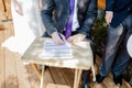 Closeup shot of a groom signing a wedding contract papers on a wooden table on a sunny day Royalty Free Stock Photo