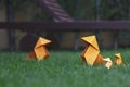Closeup shot of a group of orange origami figures on the green grass