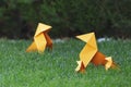 Closeup shot of a group of orange origami figures on the green grass