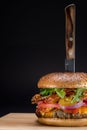 Closeup shot of a hamburger with a metal knife inserted in the center