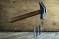 Closeup shot of a hammer floating above the nails on the wooden ground Royalty Free Stock Photo