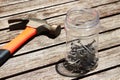 Closeup shot of a hammer near a jar filled with metal nails on a wooden surface Royalty Free Stock Photo